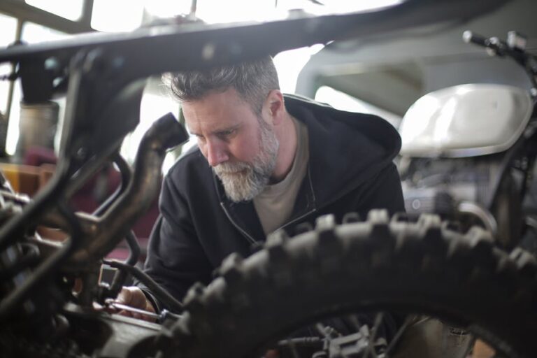 Professional mechanic working intently on motorbike in a workshop.