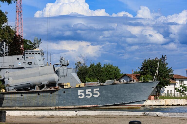 A navy patrol boat with the number 555 docked at a harbor under a scenic sky.
