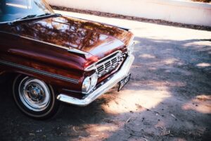 Front view of a vintage red classic car parked outside in natural light.