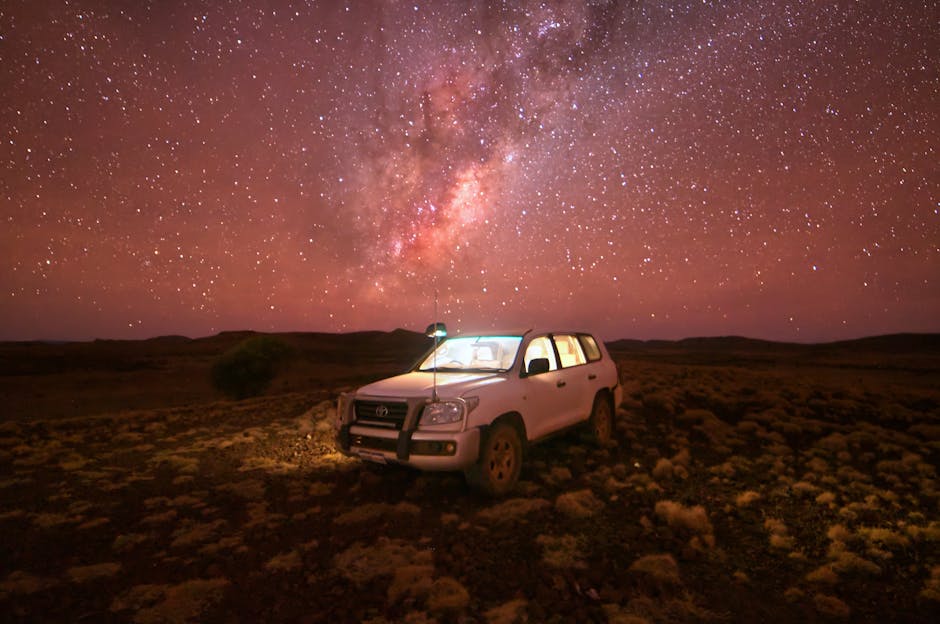 A Toyota SUV parked in a desolate landscape under a breathtaking starry night and Milky Way.