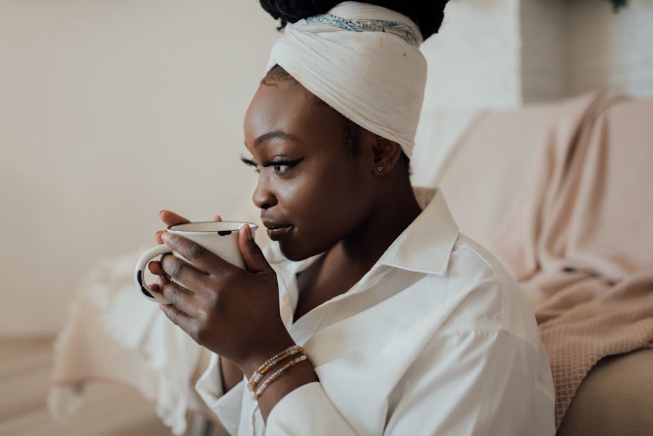 Woman with headwrap sipping coffee in cozy interior, reflecting relaxation lifestyle.