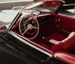 Close-up of a red interior in a classic Mercedes convertible, highlighting the steering wheel and dashboard details.