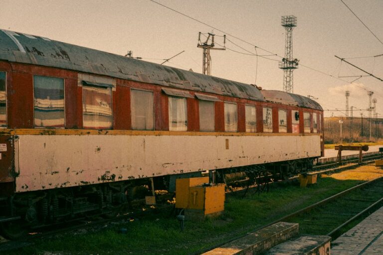 Photo of a rusted vintage train car in Varna rail yard, bathed in warm sunlight. Perfect for historical and travel themes.