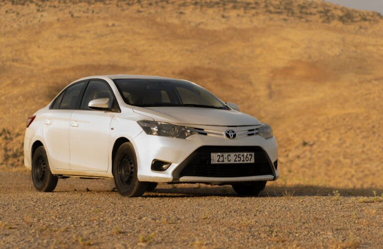 A modern white Toyota car parked in a vast desert setting, perfect for automotive imagery.