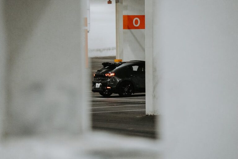 A stylish black car parked in a modern indoor parking garage with concrete pillars.