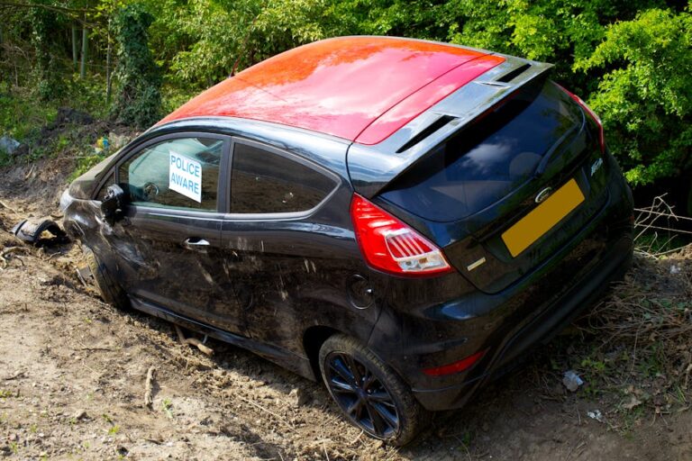 A damaged black Ford Fiesta with a sign 'Police Aware' on a dirt road in Welwyn Garden City, UK.